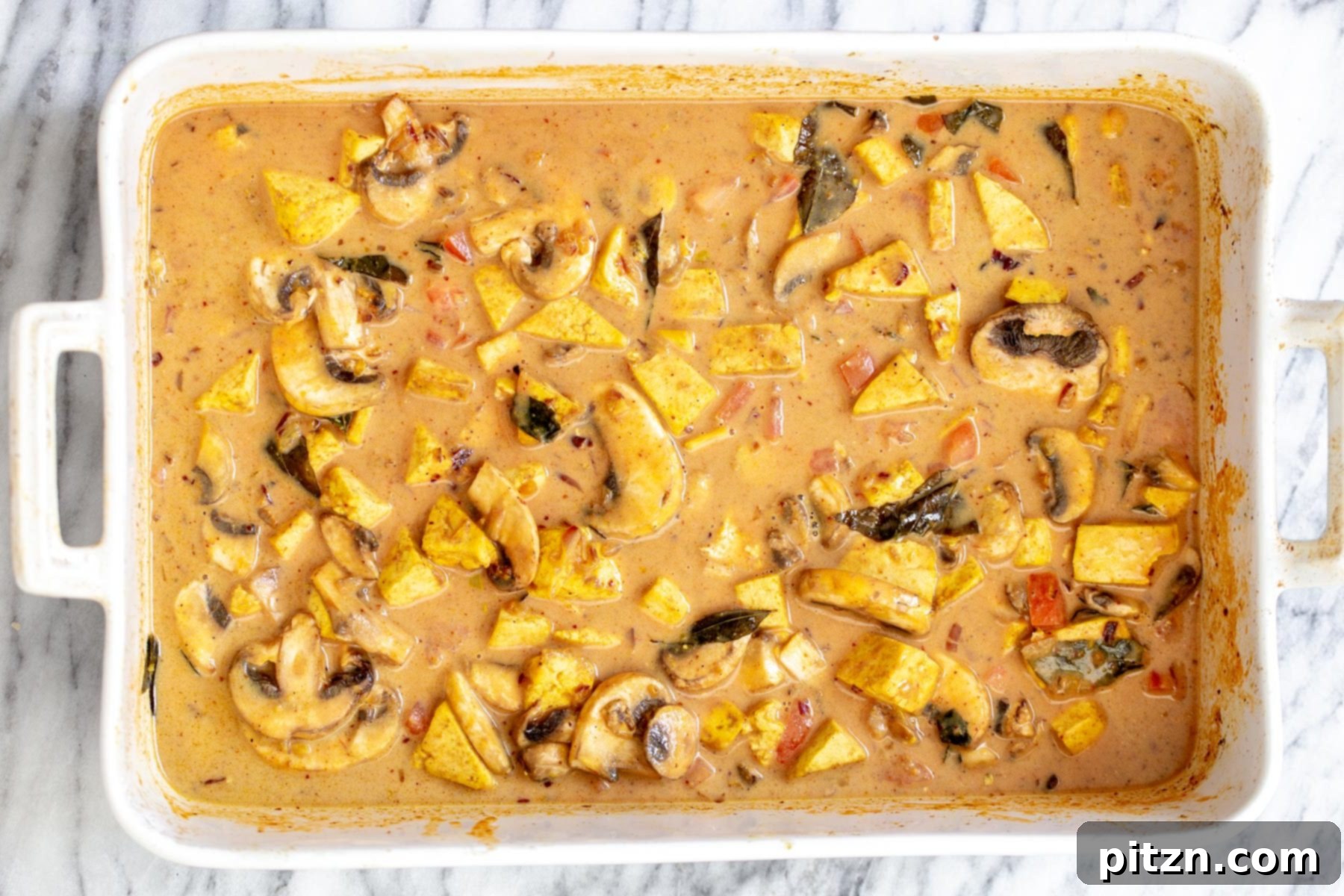 An Indian coconut milk and curry tofu casserole, perfectly assembled and ready for its final bake in the oven.
