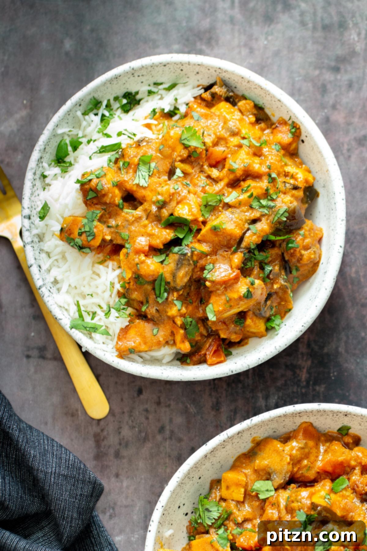A single serving of rich Indian Madras Curry tofu casserole, served elegantly with white rice and fresh cilantro garnish.