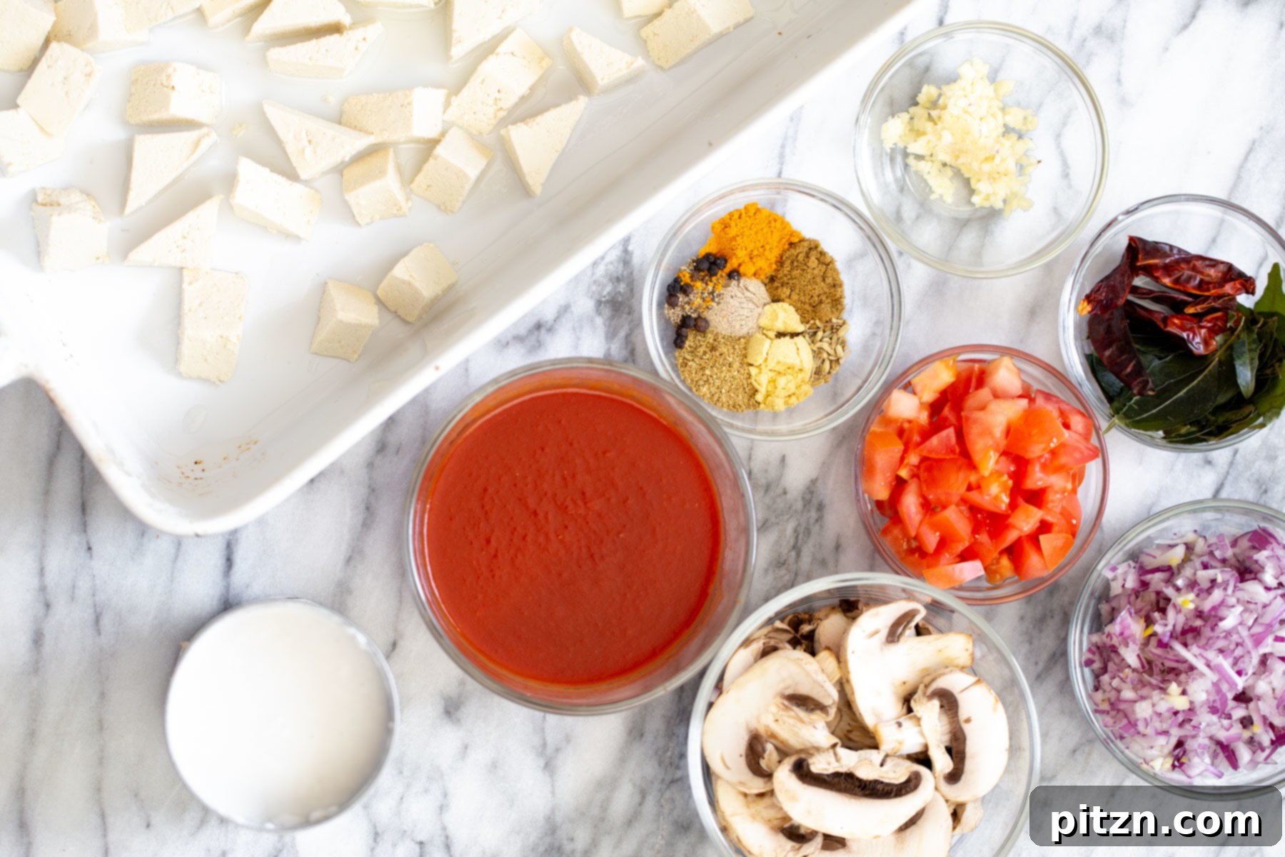 Ingredients needed for making a vibrant vegan tofu casserole, including tofu, spices, vegetables, and coconut milk.