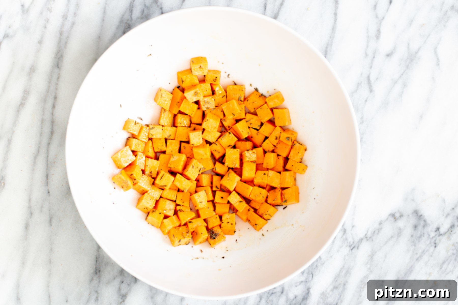 Spicy Maple Mustard Tofu and Sweet Potato Bowl 9 Sweet potato cubes beautifully mixed with seasoning and a touch of oil in a small bowl, ready for roasting.