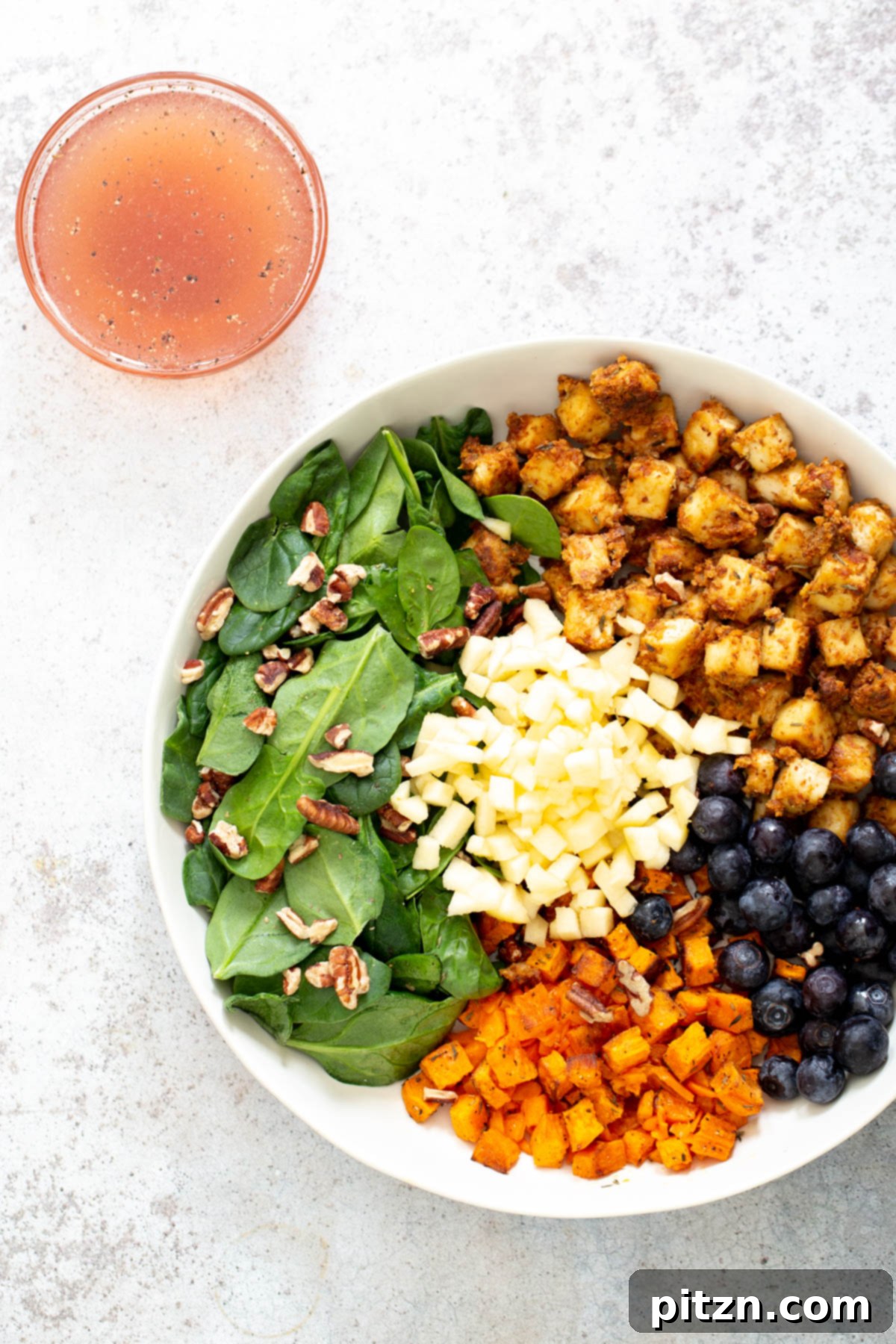 Sweet Potato Tofu Bowl A beautifully assembled vegan sweet potato tofu bowl with all its components, accompanied by a small side dish of the luscious maple lime dressing.