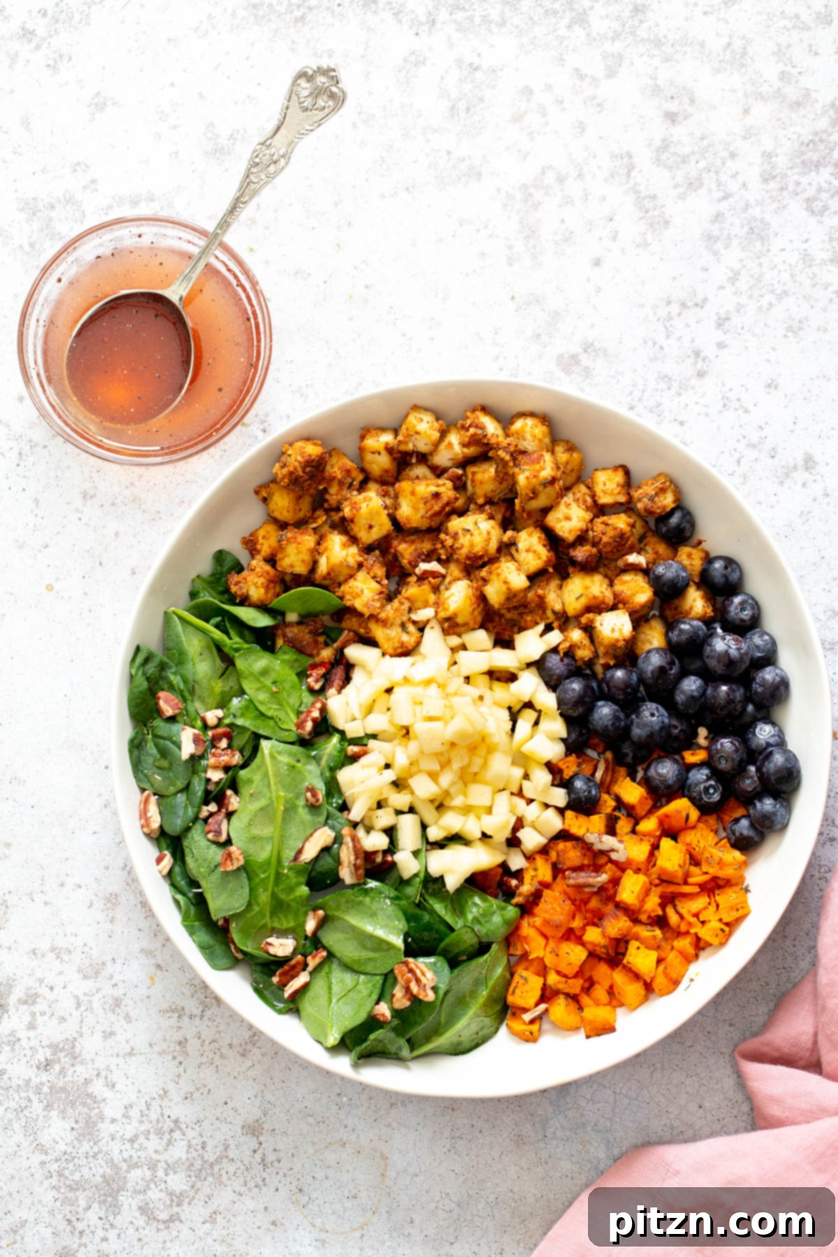 Sweet Potato Tofu Bowls All fresh ingredients for the Spicy Maple Mustard Tofu Bowl, including sweet potatoes, tofu, apples, blueberries, and pecans, artfully arranged in a shallow white bowl.