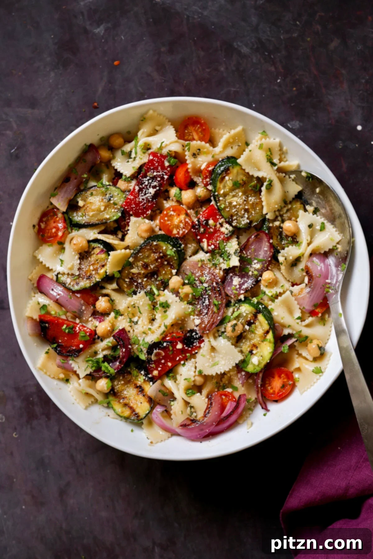 A beautifully presented bowl of easy summer pasta salad with grilled vegetables, ready to be served at a potluck or picnic.