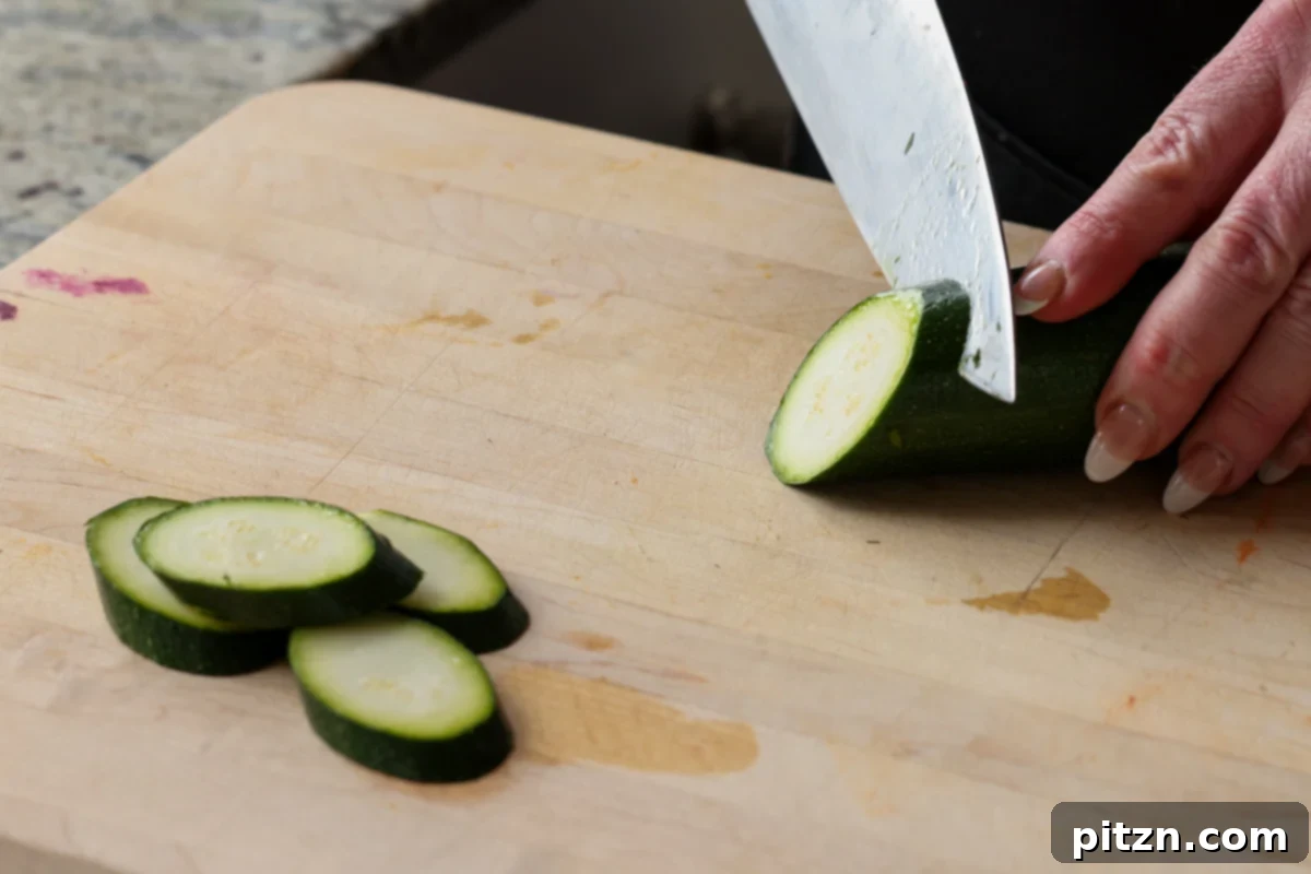 Chef precisely slicing a zucchini into 1/4-inch thick diagonal pieces, preparing them for grilling.
