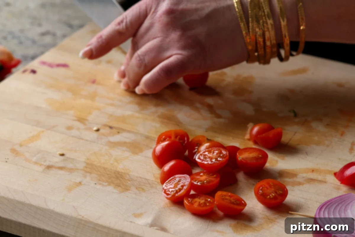 Fresh cherry tomatoes being sliced, ready to be added to the summer pasta salad for a burst of juicy flavor.