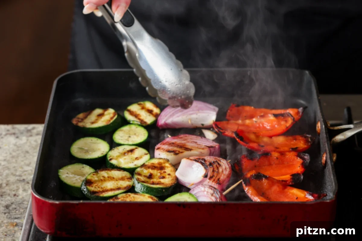 A spatula flipping grilled vegetables on a hot grill pan, showcasing the delicious char marks forming.
