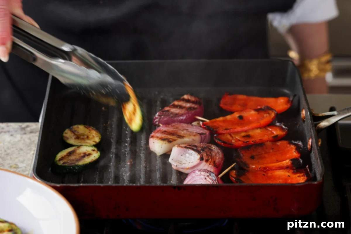 Removing cooked, charred vegetables from the grill pan, their vibrant colors and smoky aroma promising deliciousness.