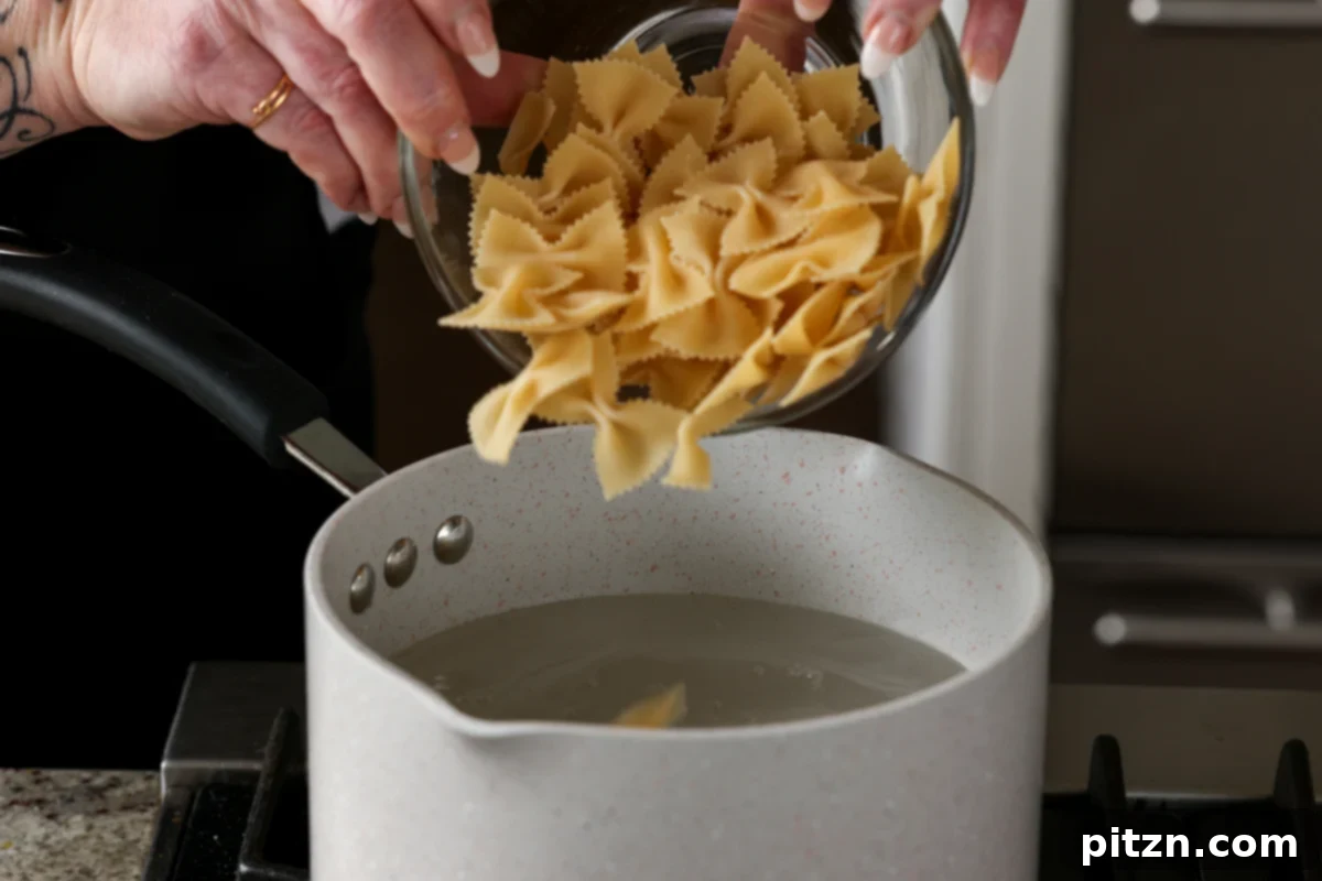 Adding pasta to a pot of boiling water seasoned with salt, garlic powder, and Italian herbs.