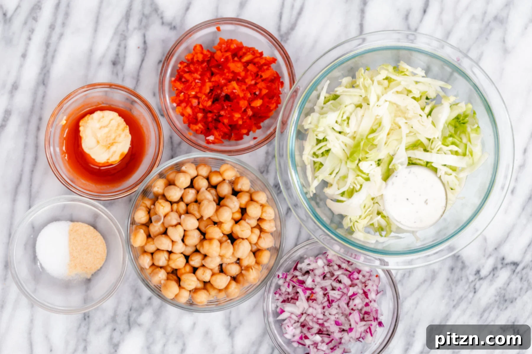 A beautiful flat lay of fresh ingredients for the Buffalo Chickpea Salad Sandwich, neatly arranged on a marble countertop, showcasing vibrant colors.