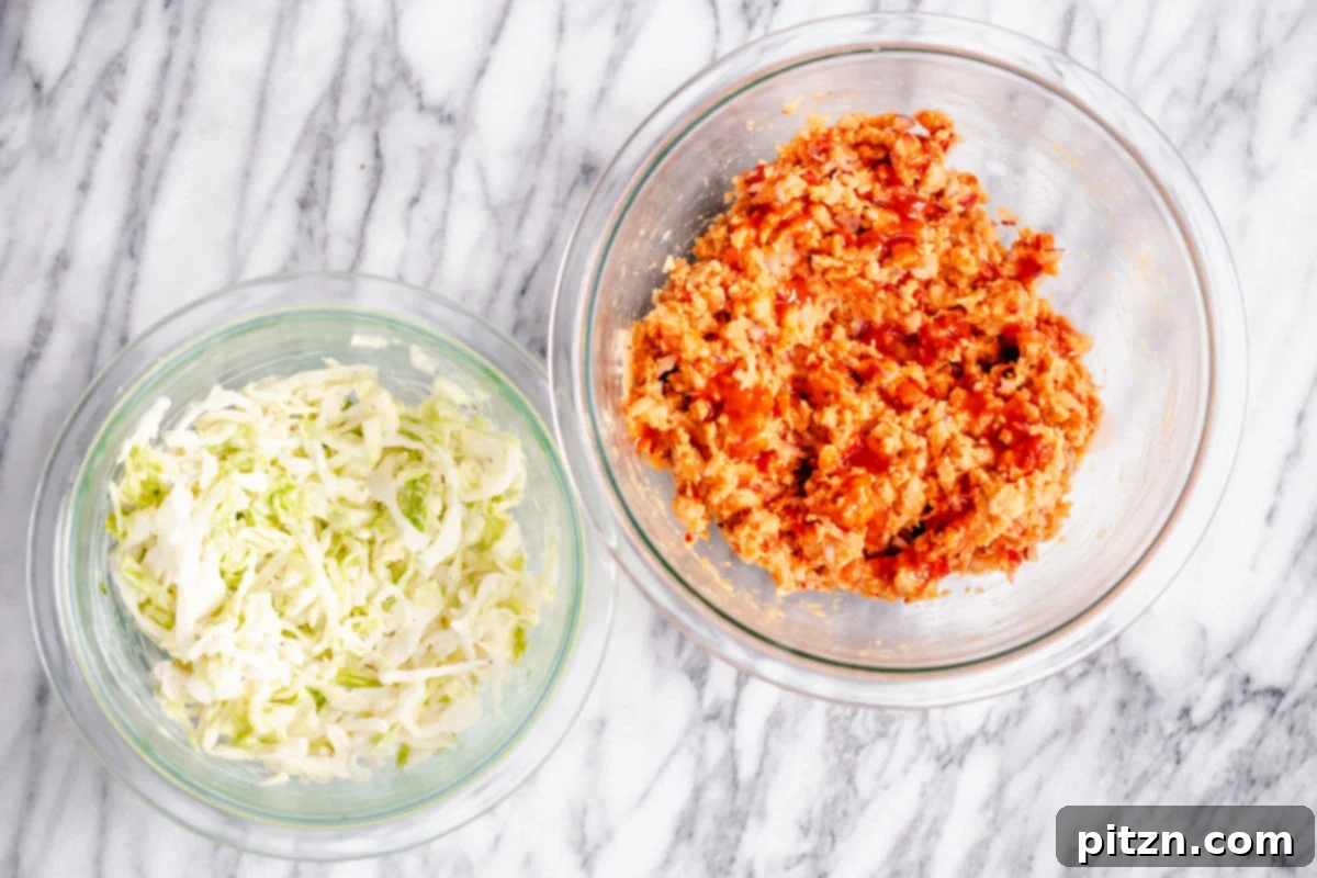 Two glass bowls on a marble countertop, one filled with prepared crunchy slaw and the other with spicy buffalo chickpea salad.