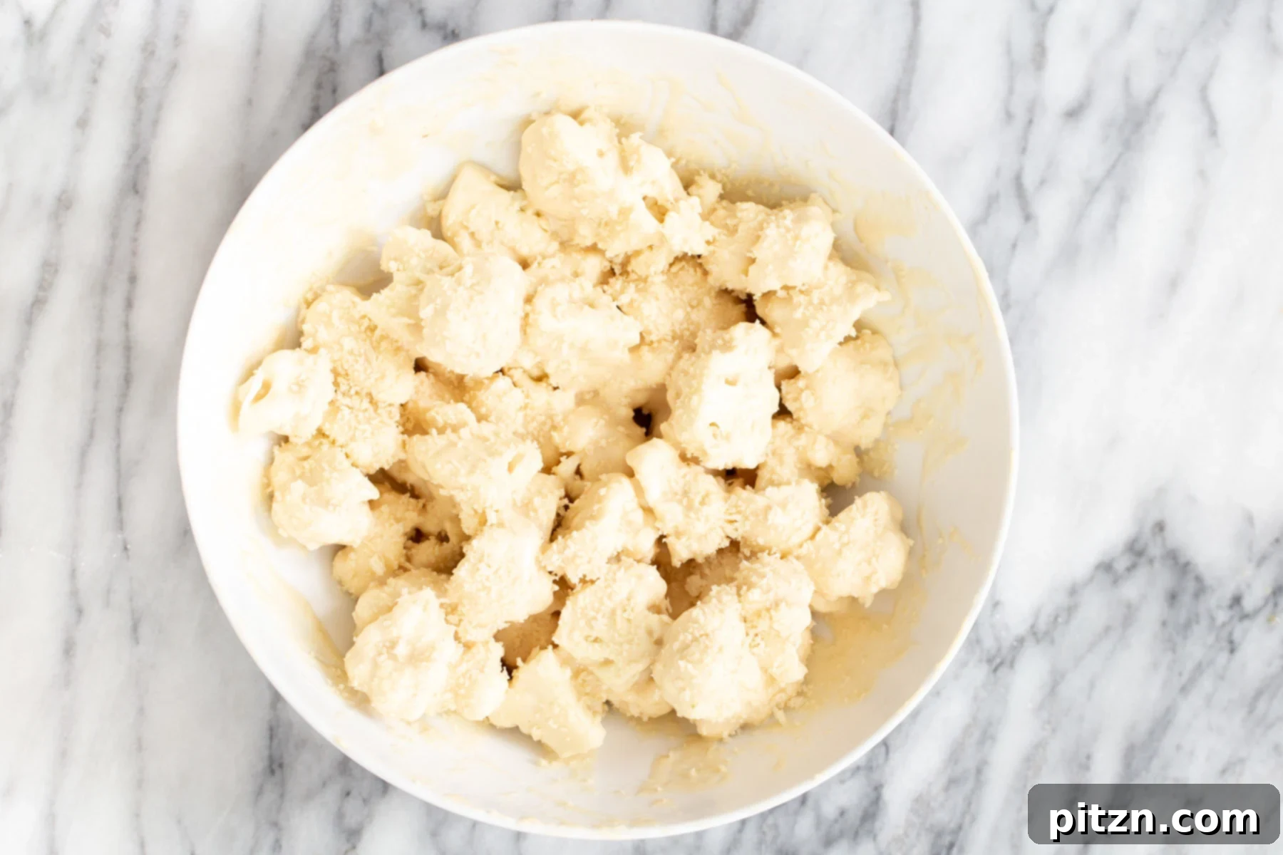 Golden Baked Cauliflower Manchurian 8 Battered cauliflower florets being tossed with panko breadcrumbs to create a crispy coating for Gobi Manchurian