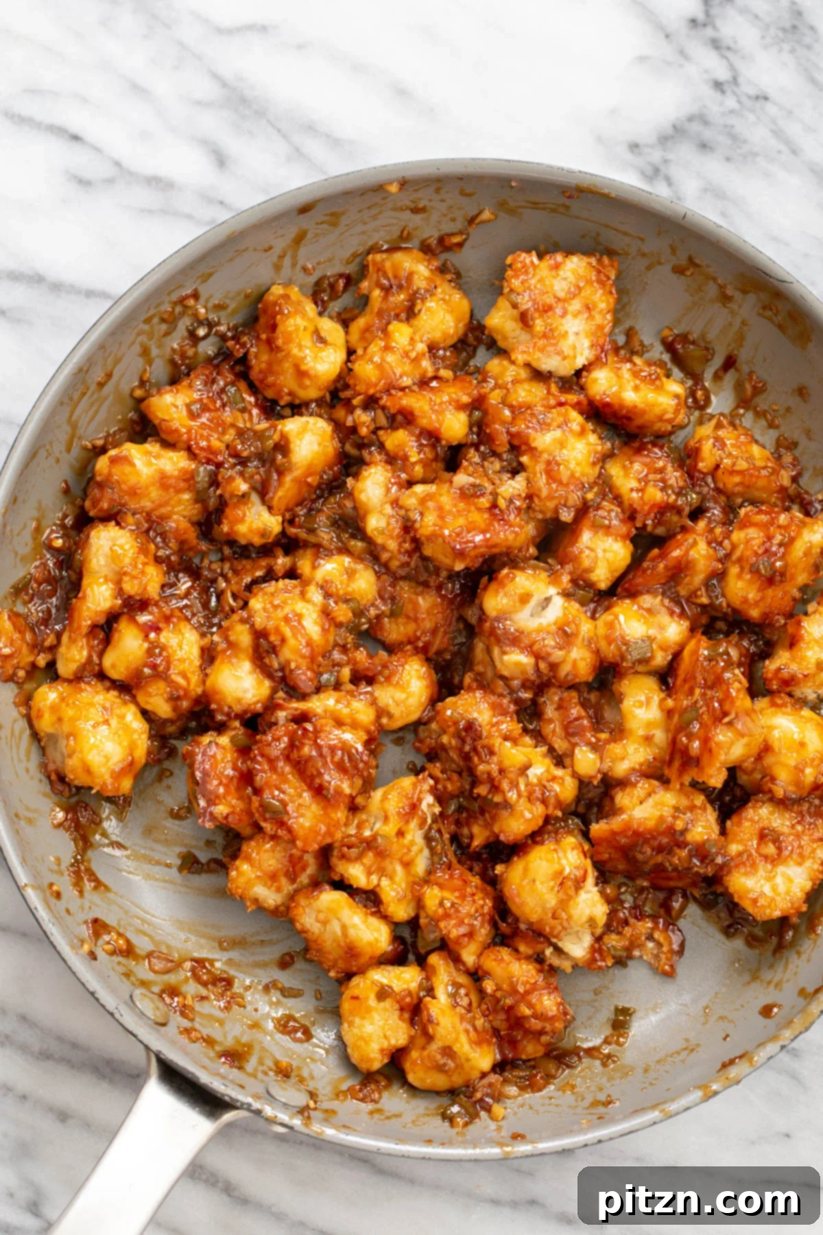Golden Baked Cauliflower Manchurian 4 A vibrant close-up of vegan Cauliflower Manchurian simmering in a saucepan, showcasing the rich, glossy sauce