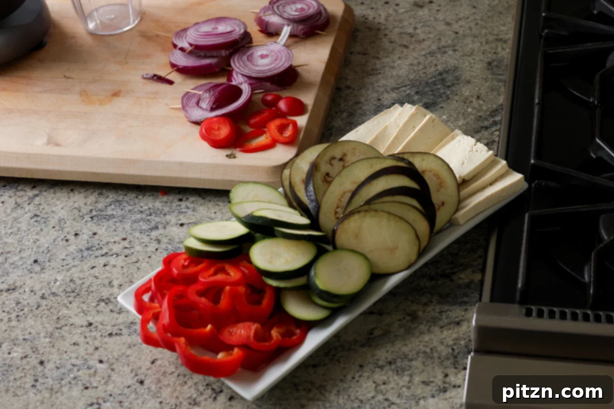 Mediterranean Grilled Veggie with Sun-Kissed Tomato & Basil Pesto 6 sliced veggies, ready for grilling, arranged neatly on a cutting board