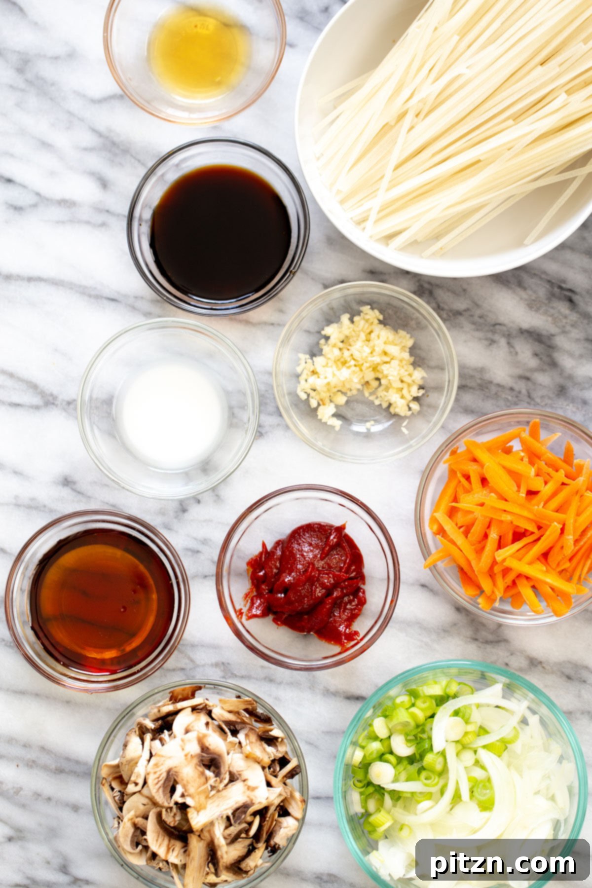 A vibrant selection of ingredients for Korean Gochujang Noodles, including rice noodles, fresh vegetables, and the signature gochujang paste, arranged neatly before cooking.