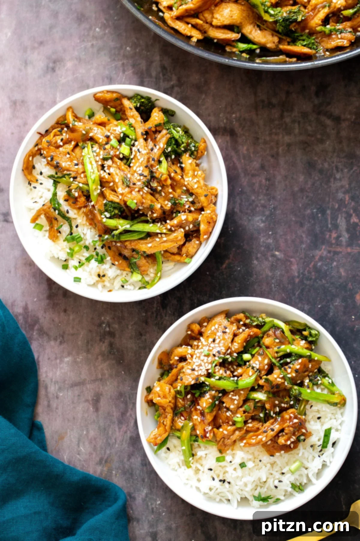 Two white bowls filled with sesame soy curl stir-fry, garnished with sesame seeds and green onions, served alongside white rice