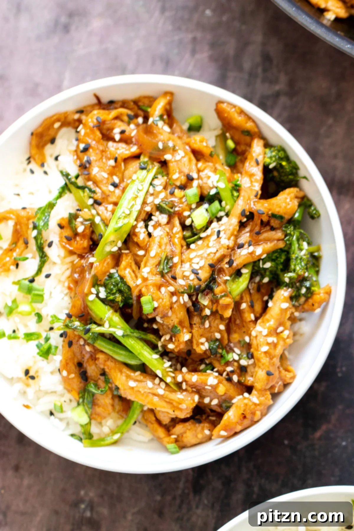 A perfectly portioned bowl of sesame soy curl stir-fry with rice, garnished with sesame seeds and green onions