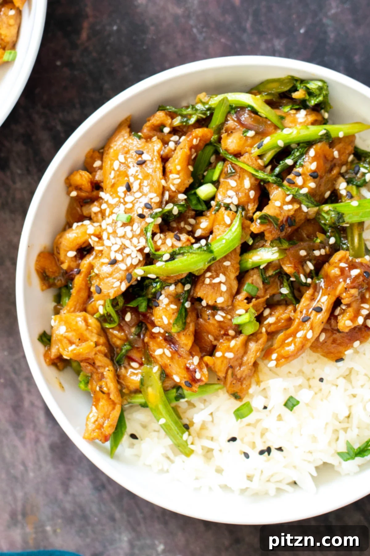 Close-up overhead view of sesame shallot soy curl stir-fry with vibrant broccolini, garnished with sesame seeds in a serving bowl