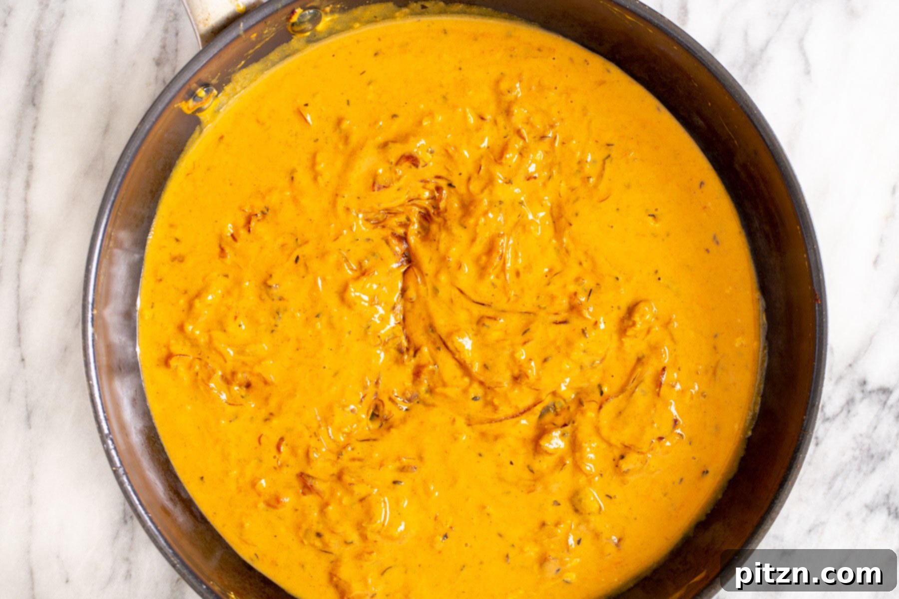 Rich Double Onion Cauliflower 13 Golden-brown cauliflower florets are gently introduced into a simmering tomato-yogurt gravy in a black skillet, ready to absorb the rich flavors.