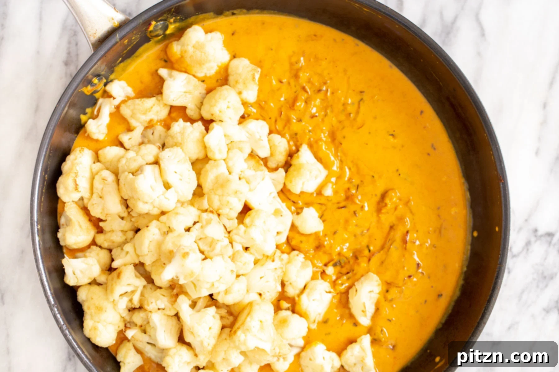 Rich Double Onion Cauliflower 14 Cauliflower florets luxuriate in a bubbling, aromatic onion gravy within a saucepan, slowly tenderizing and absorbing the complex flavors.