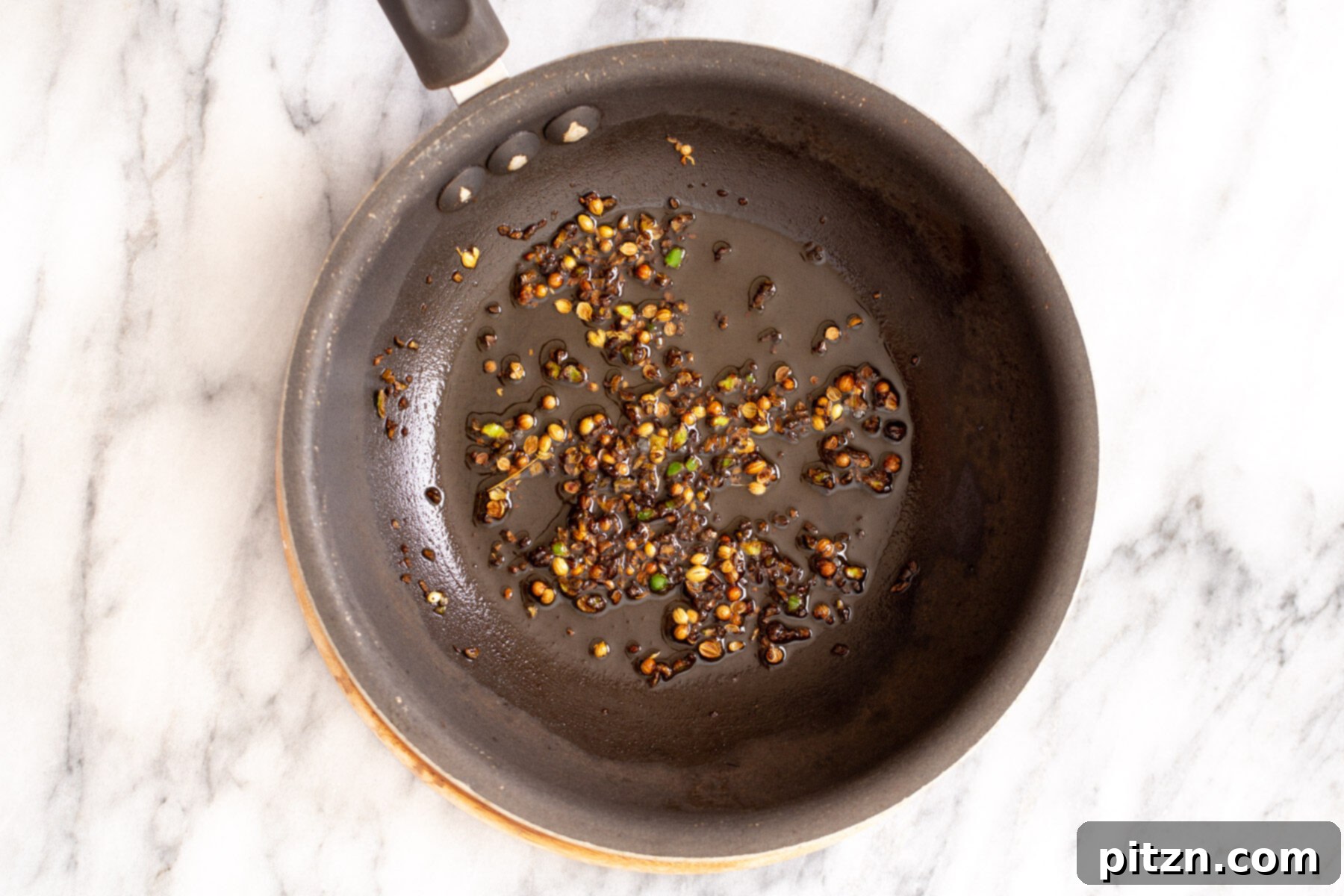 Rich Double Onion Cauliflower 16 Whole spices, specifically crushed coriander seeds and green chilies, gently simmer in hot oil to create the aromatic tempering mixture for the Indian curry.