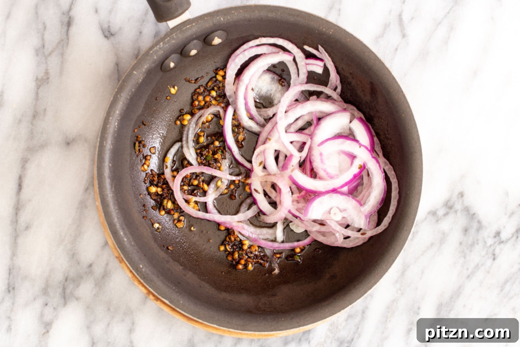 Rich Double Onion Cauliflower 17 A vibrant mix of whole spices and thinly sliced onions sizzle in a frying pan, creating the final aromatic tempering for the Gobi Do Pyaza.