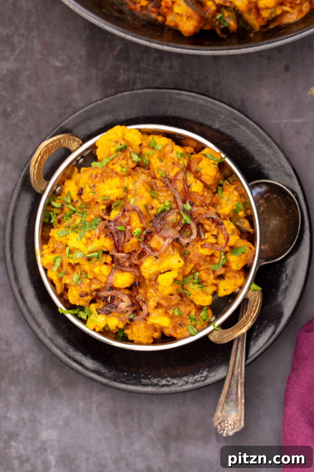 gobi Do Pyaza Gluten-free Indian Gobi Do Pyaza, a cauliflower curry, presented beautifully in an Indian serving dish with a spoon resting beside it, garnished and ready to be enjoyed.