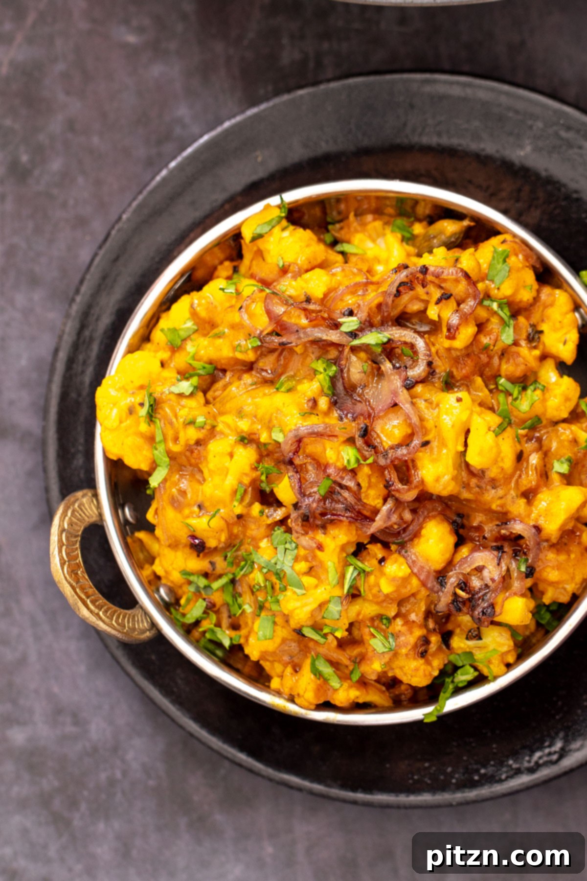 Rich Double Onion Cauliflower 3 A vibrant Indian Gobi Do Pyaza cauliflower curry with rich onion gravy, served elegantly in a traditional Indian dish, garnished with fresh herbs.