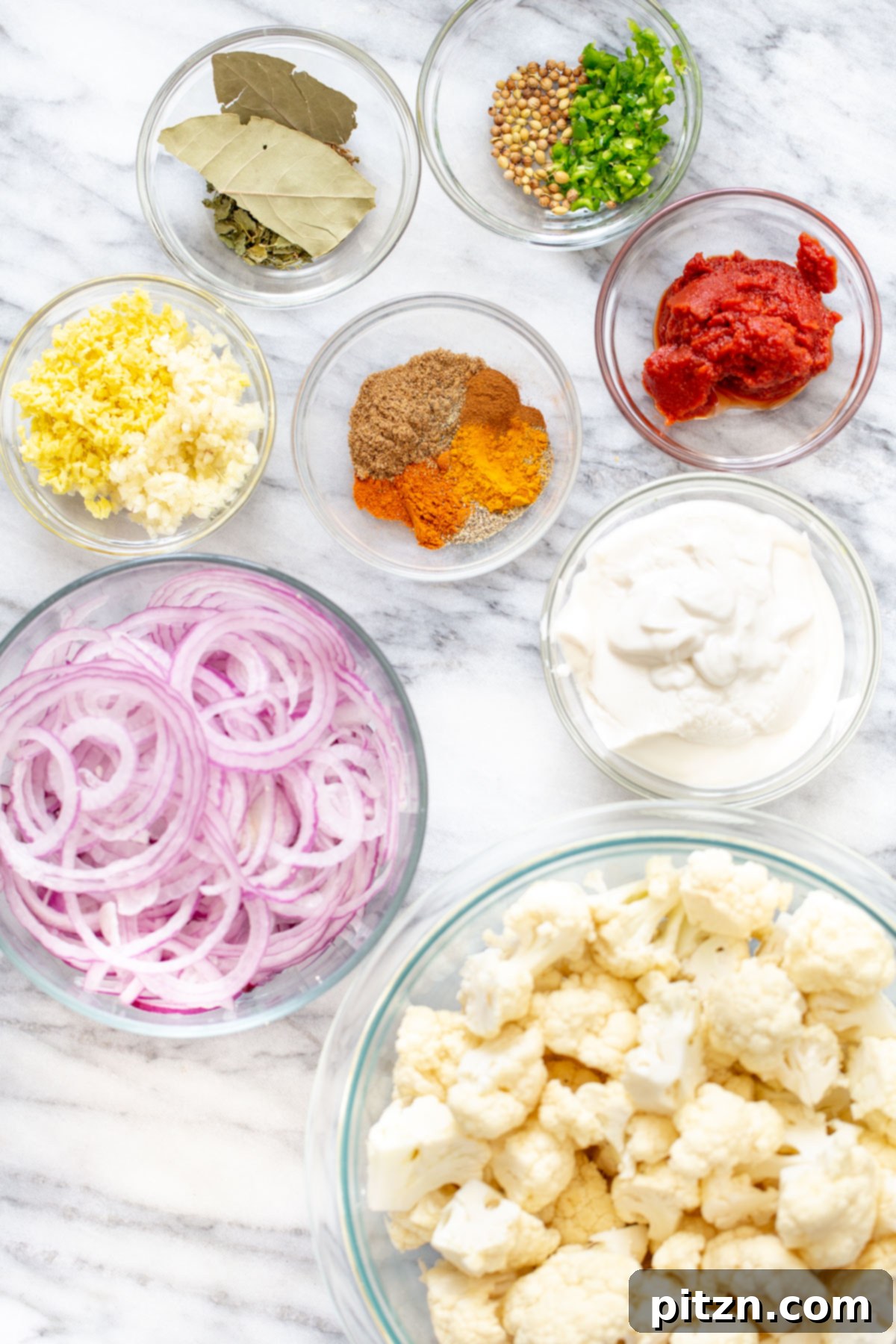 Rich Double Onion Cauliflower 5 A vibrant selection of ingredients laid out, including cauliflower florets, onions, various whole and ground spices, and fresh herbs, all ready for making a delicious Indian cauliflower curry.
