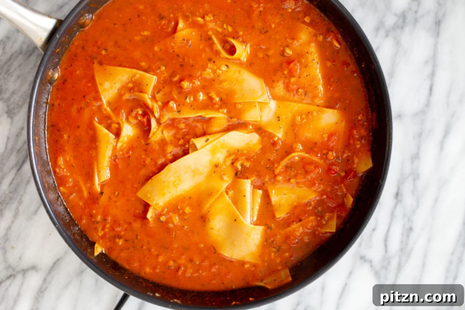 Hearty Vegan Skillet Lasagna 10 The vegan skillet lasagna bolognese simmering in a black skillet, showing the noodles absorbing the rich sauce and becoming tender.