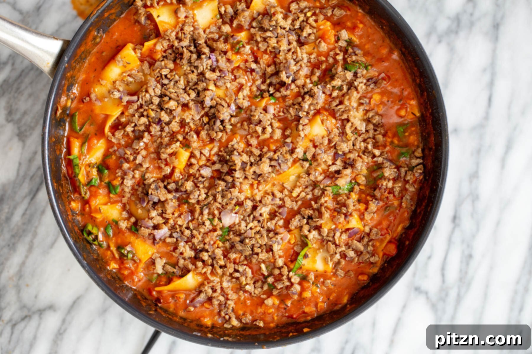 Hearty Vegan Skillet Lasagna 12 A rustic image of vegan cast iron skillet lasagna, generously topped with savory vegan meat crumbles, showcasing its comforting appeal.