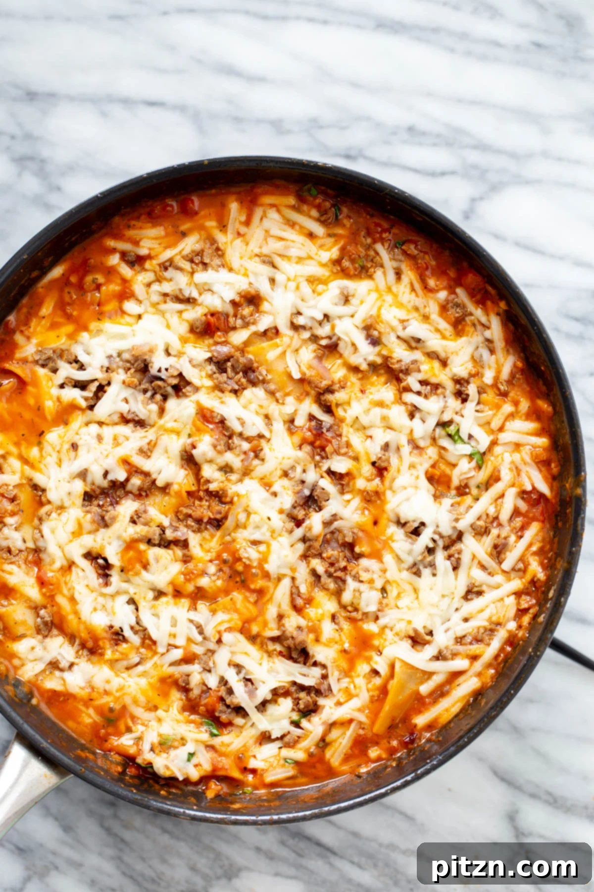 vegan skillet lasagna A close-up shot of vegan skillet lasagna with perfectly melted vegan cheese shreds, nestled in a black iron skillet, highlighting its creamy, inviting texture.
