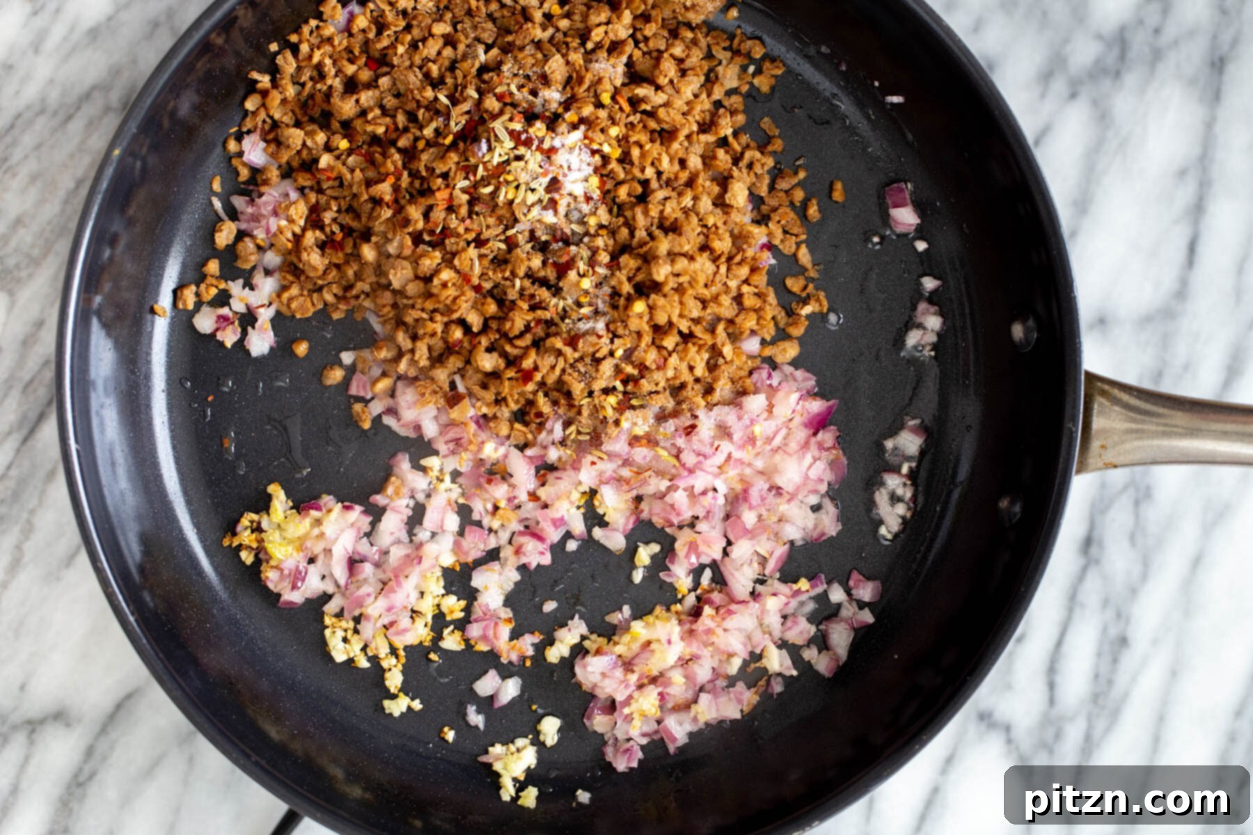 Hearty Vegan Skillet Lasagna 8 Vegan veggie crumbles being added to the sautéed onions and garlic in a black skillet, ready to be browned and infused with flavor.