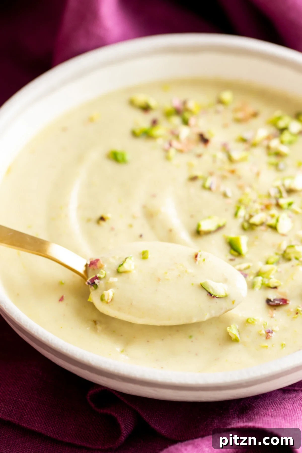 A spoon being dipped into a bowl of Vegan Rabri, a creamy Indian dessert