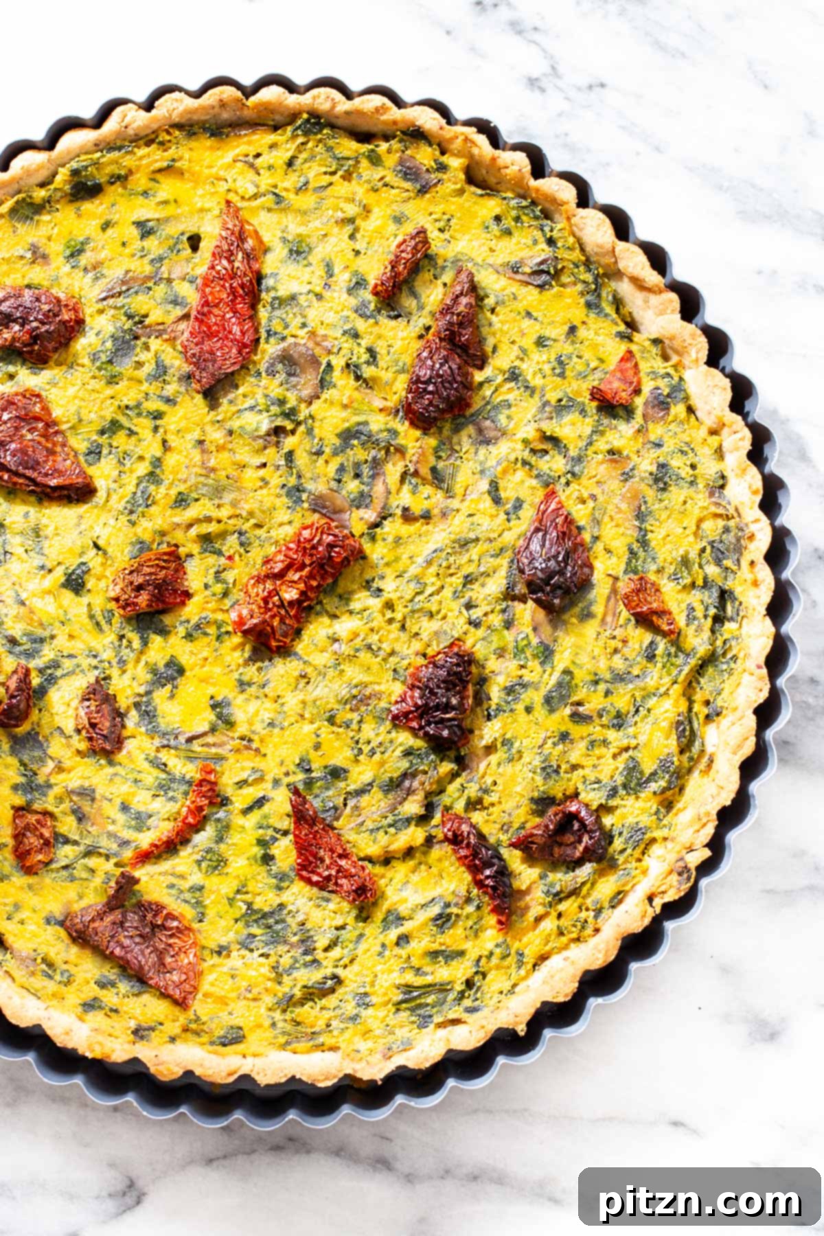 Freshly Baked Vegan Quiche Freshly baked vegan quiche, golden brown and bursting with mushrooms, spinach, and leeks, cooling in a tart pan on a wire rack.