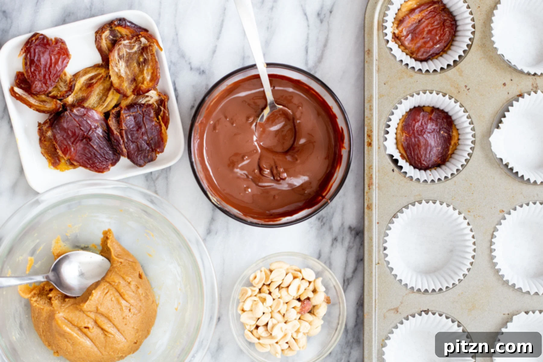 Halved, pitted Medjool dates being carefully added on top of the peanut nougat layer in chocolate cups, creating the caramel-like center.