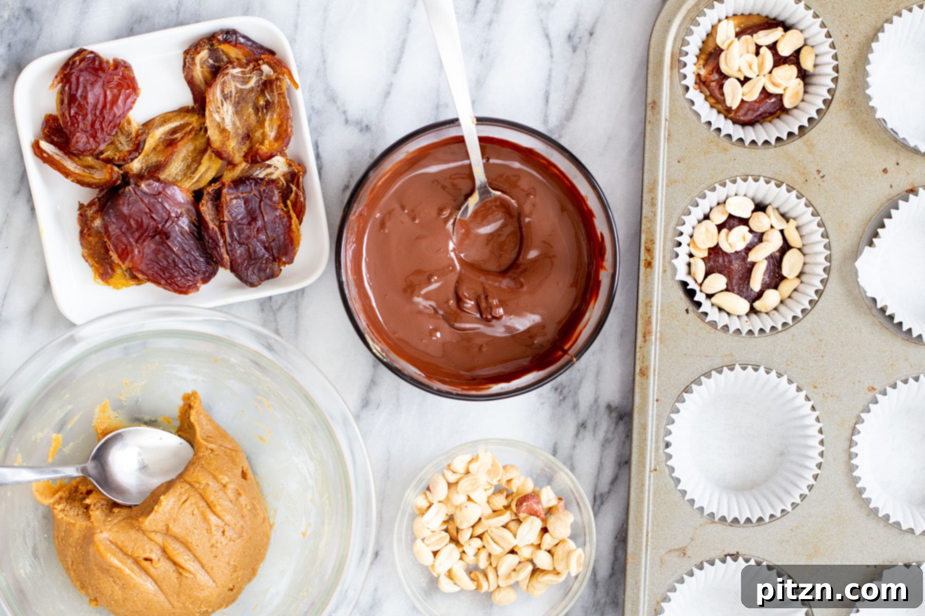 Roasted peanuts being sprinkled over the date and nougat layers in chocolate cups, adding a crunchy texture to the vegan snickers.