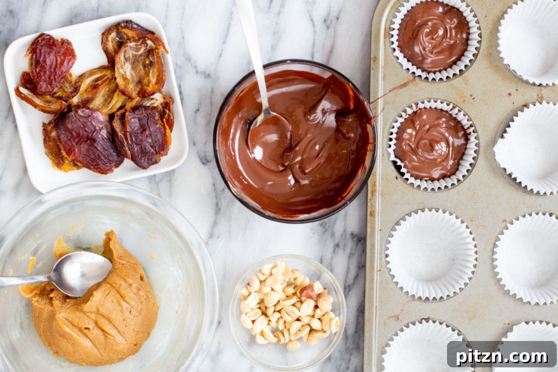 Melted chocolate being drizzled and spread over the peanut and date layers, completing the top coating of the vegan snickers cups.