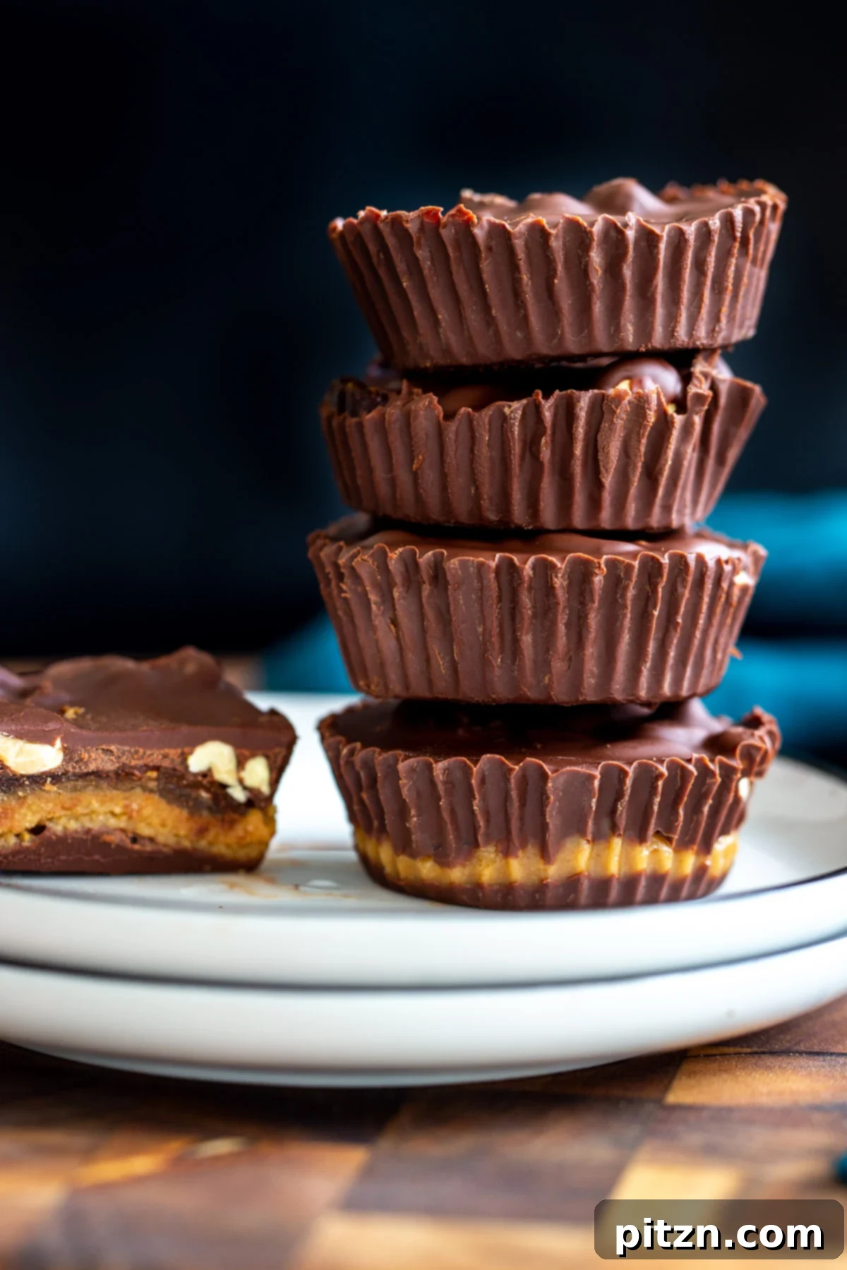Stacked vegan peanut butter cups with visible layers of chocolate, peanut butter nougat, and dates.