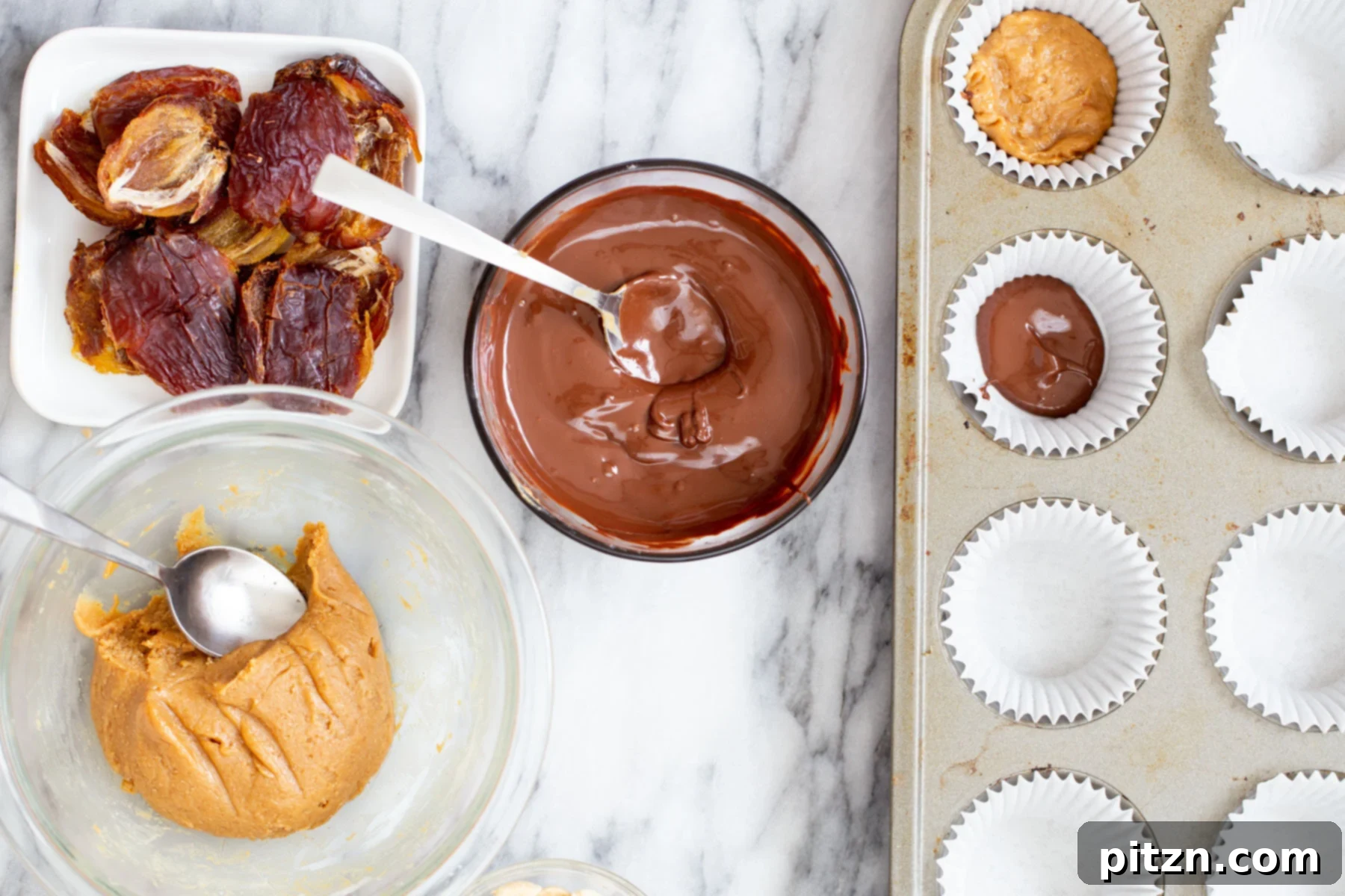A ball of peanut butter nougat being placed onto the melted chocolate base in a muffin liner, forming the next layer of the vegan snickers cup.