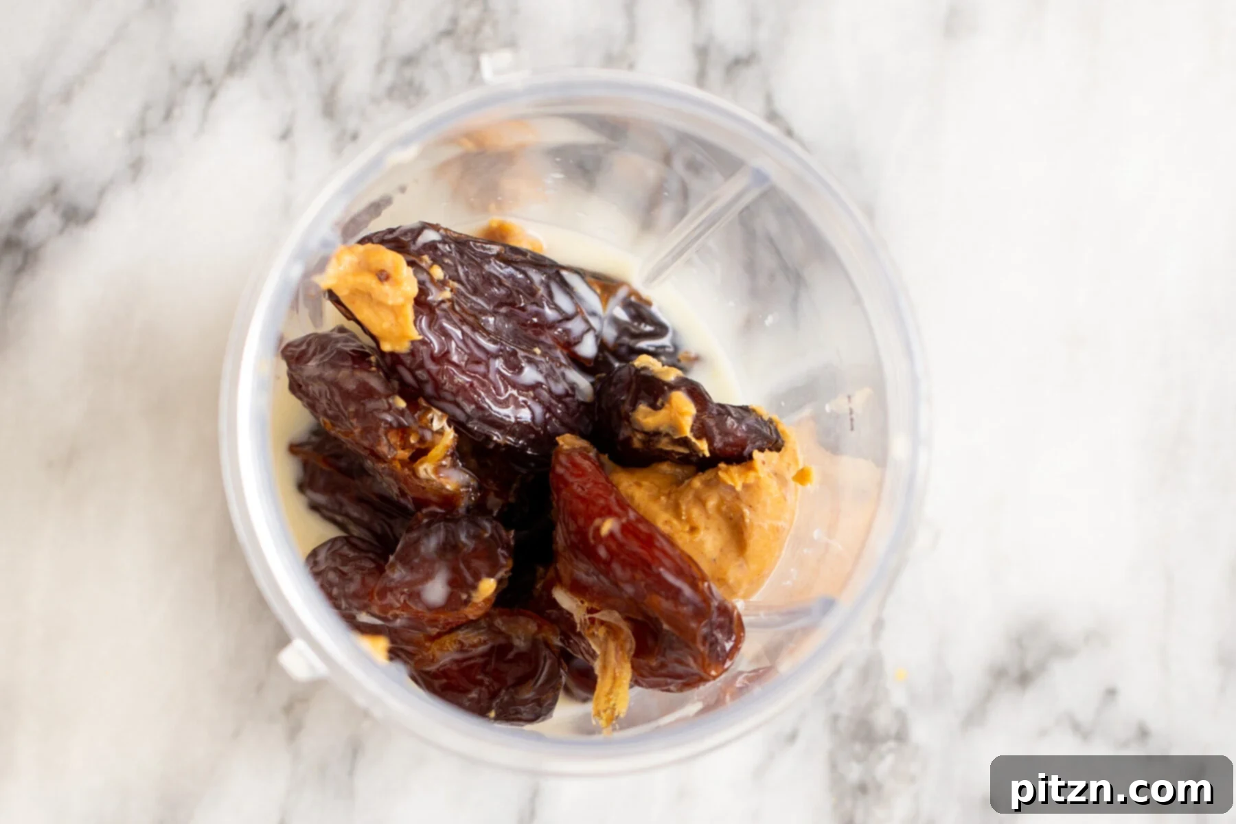 Date Caramel Ingredients in Blender Medjool dates, almond butter, and non-dairy milk in a blender, poised to be transformed into luscious date caramel.