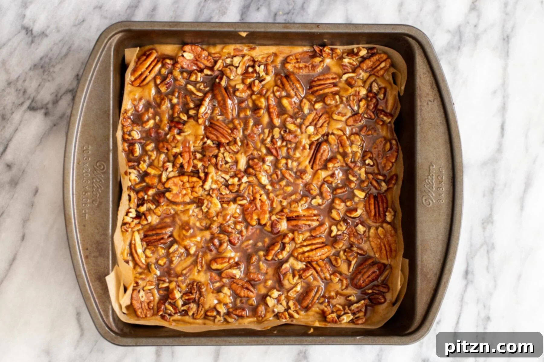 Pecan Topping on Pecan Pie Bars The shortcrust pastry base now topped with the gooey date caramel and a generous layer of spiced pecans, ready for final baking.