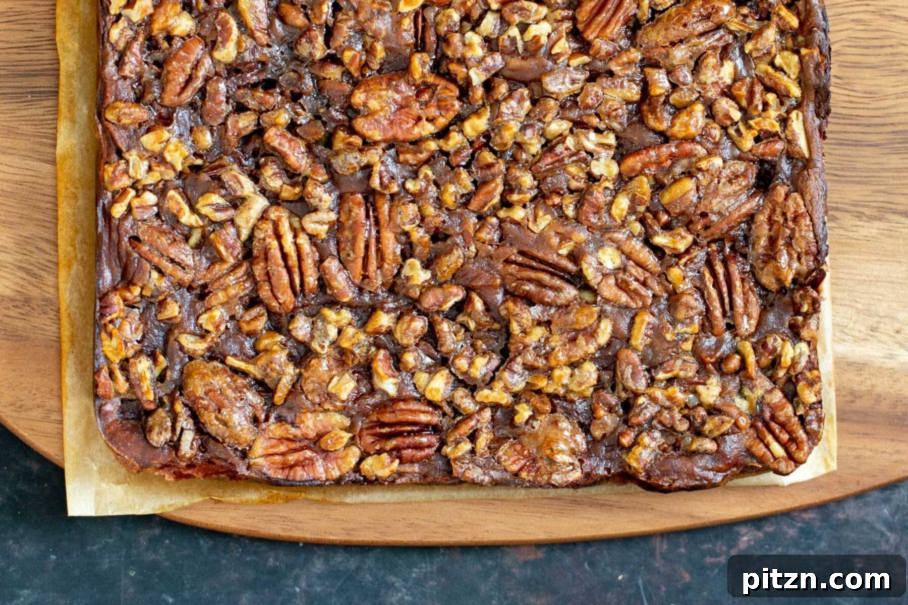 Cooled Vegan Pecan Pie Bars Freshly baked vegan pecan pie bars cooling on a wooden chopping board, displaying their rich textures.