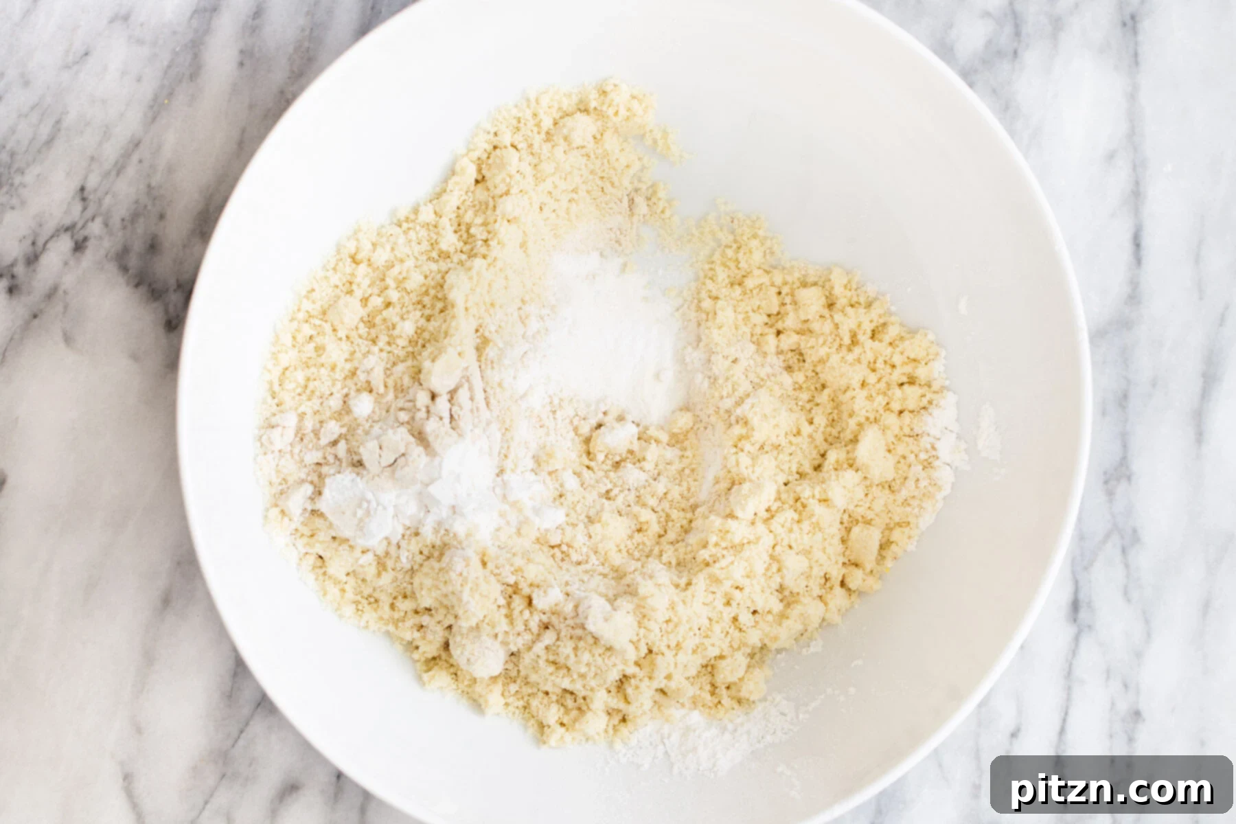 Crust Dry Mix for Vegan Pecan Pie Bars Dry ingredients for the vegan pecan pie bar crust mixed in a white bowl, showing a fine, even consistency.