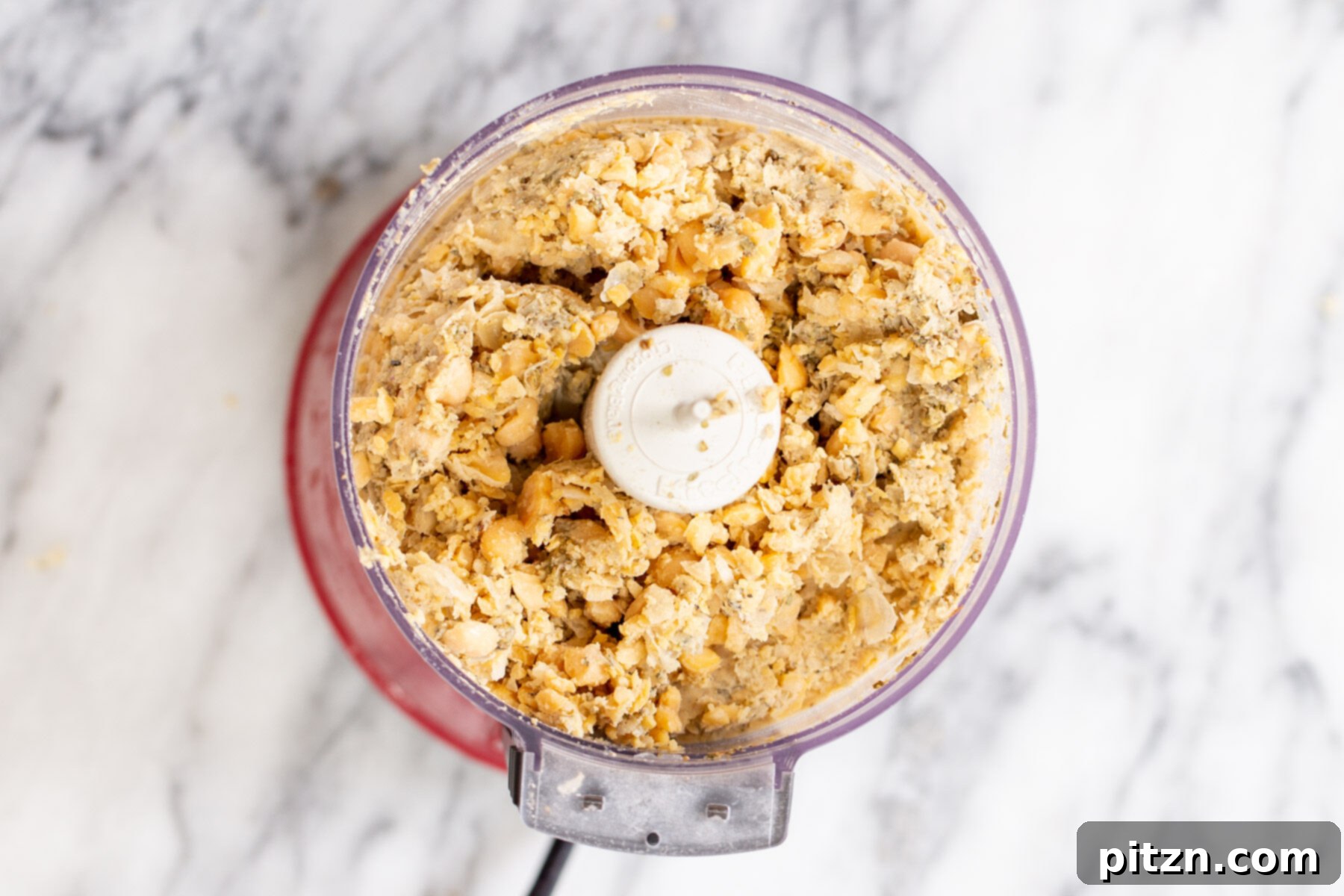 The completed vegan chickpea sausage mixture, crumbly and well-blended, resting in the food processor.