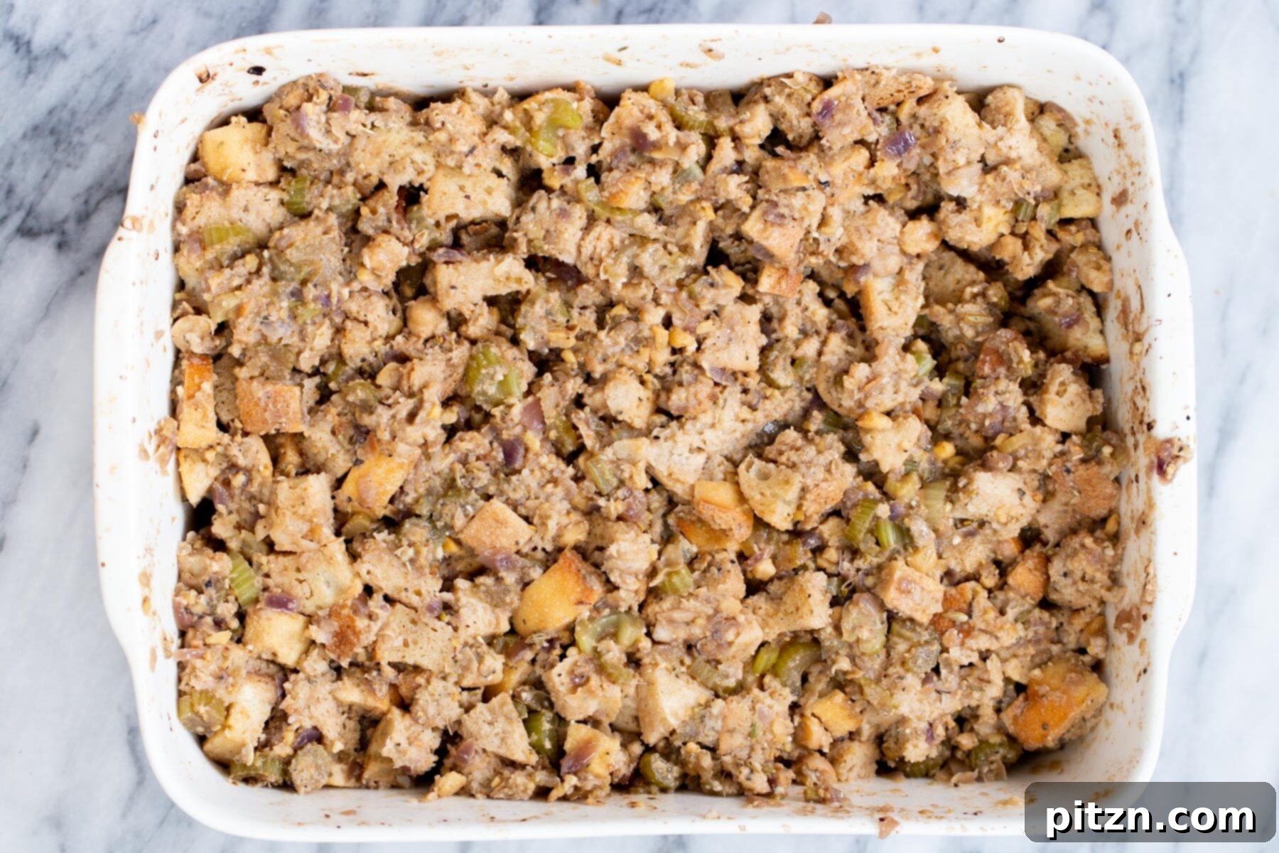 The assembled vegan stuffing mixture, moist and ready for baking, in a white casserole dish.