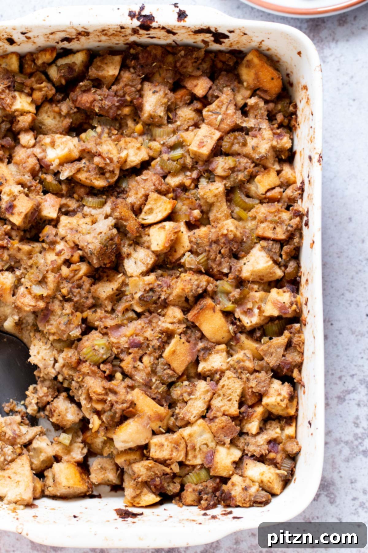 A close-up shot of vegan stuffing served in a elegant white casserole dish, ready to be enjoyed.