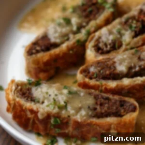An appetizing angled shot of a slice of Vegan Lentil Wellington on a plate, revealing its flaky puff pastry crust and savory lentil and mushroom filling, served with a side of rich gravy.