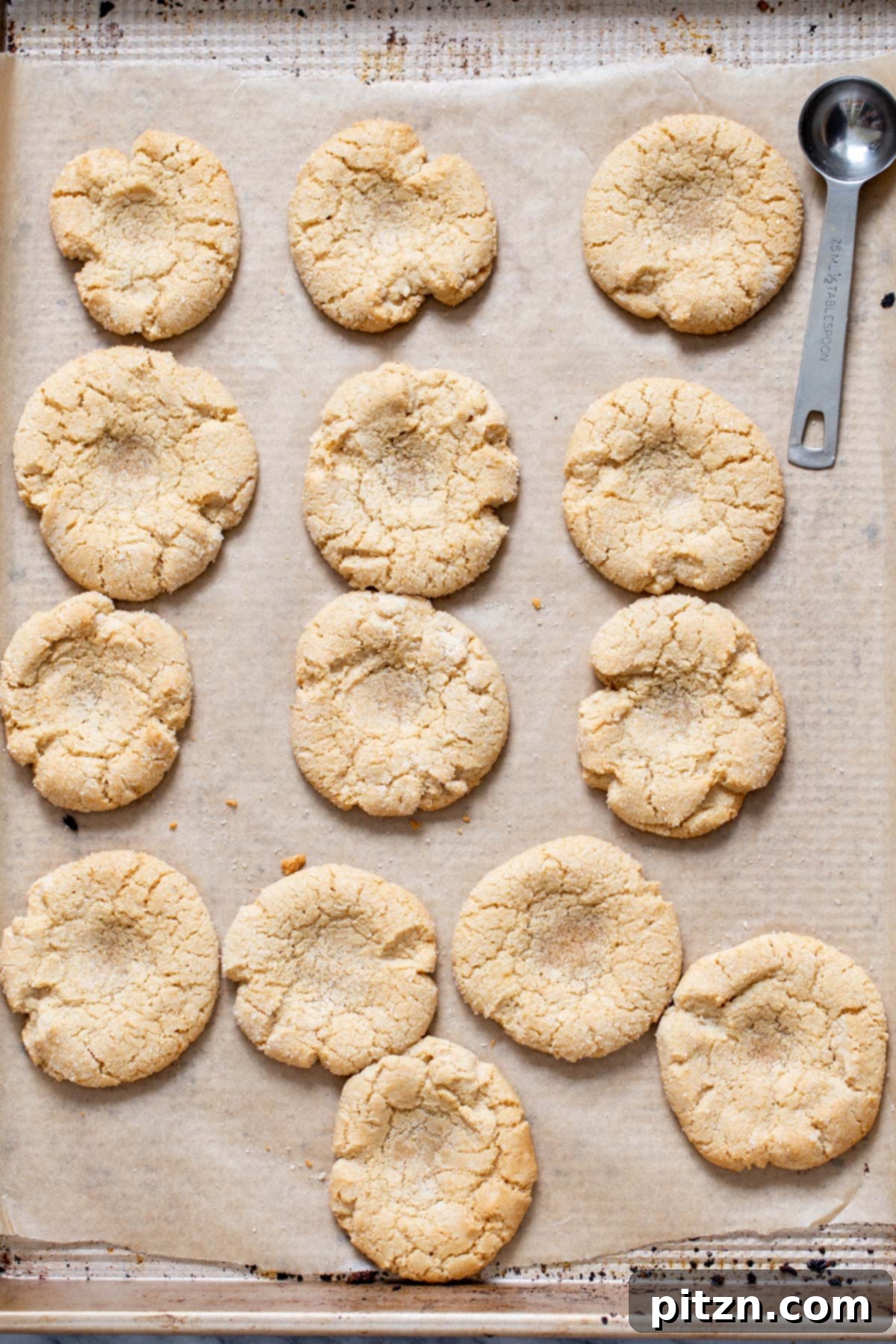 Divine Vegan Gluten-Free Chocolate Thumbprints 5 Freshly baked vegan gluten-free thumbprint cookies cooling on a baking sheet, with visible indents.