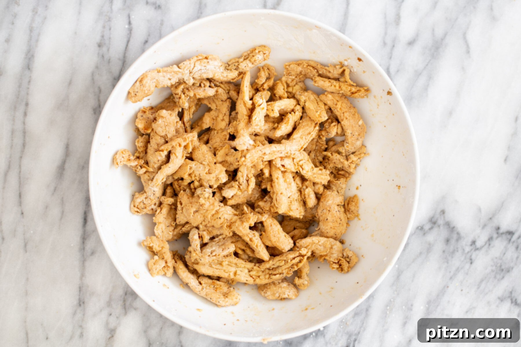 Close-up of marinated and cornstarch-coated soycurls in a bowl, showcasing the readiness for cooking.