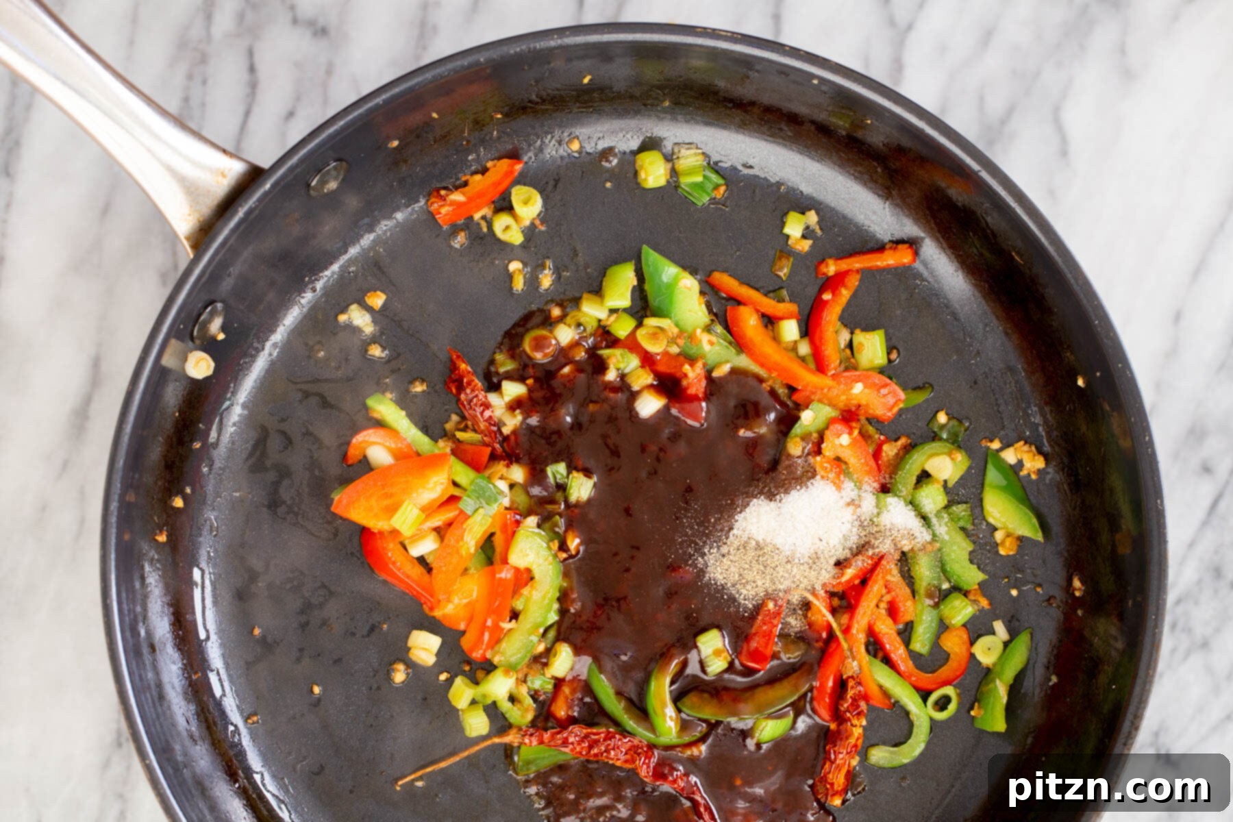 Soy sauce and sambal oelek being poured into the sautéing pan with vegetables, creating the base for the Dragon Chicken sauce.